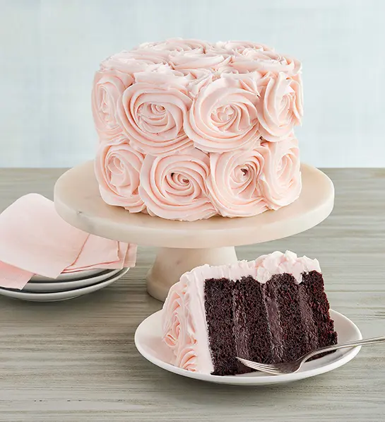 Pink frosted rose cake on a cake stand.