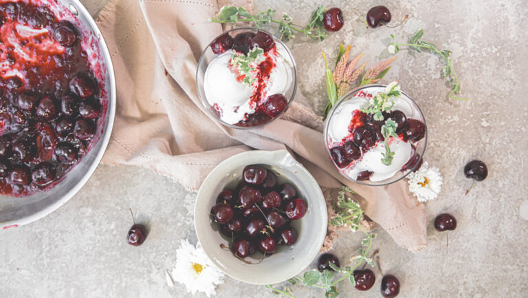 Cherry jubilee recipe with two bowls of jubilee and ice cream and a bowl of stewed cherries.