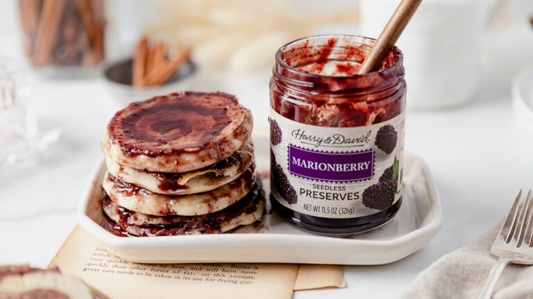 Marionberry pancakes on a plate covered with marionberry preserves.