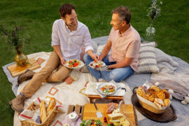 Date ideas with a couple having a picnic outside with an array of appetizers on a blanket.
