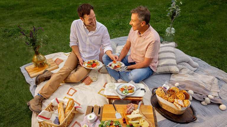 Date ideas with a couple having a picnic outside with an array of appetizers on a blanket.