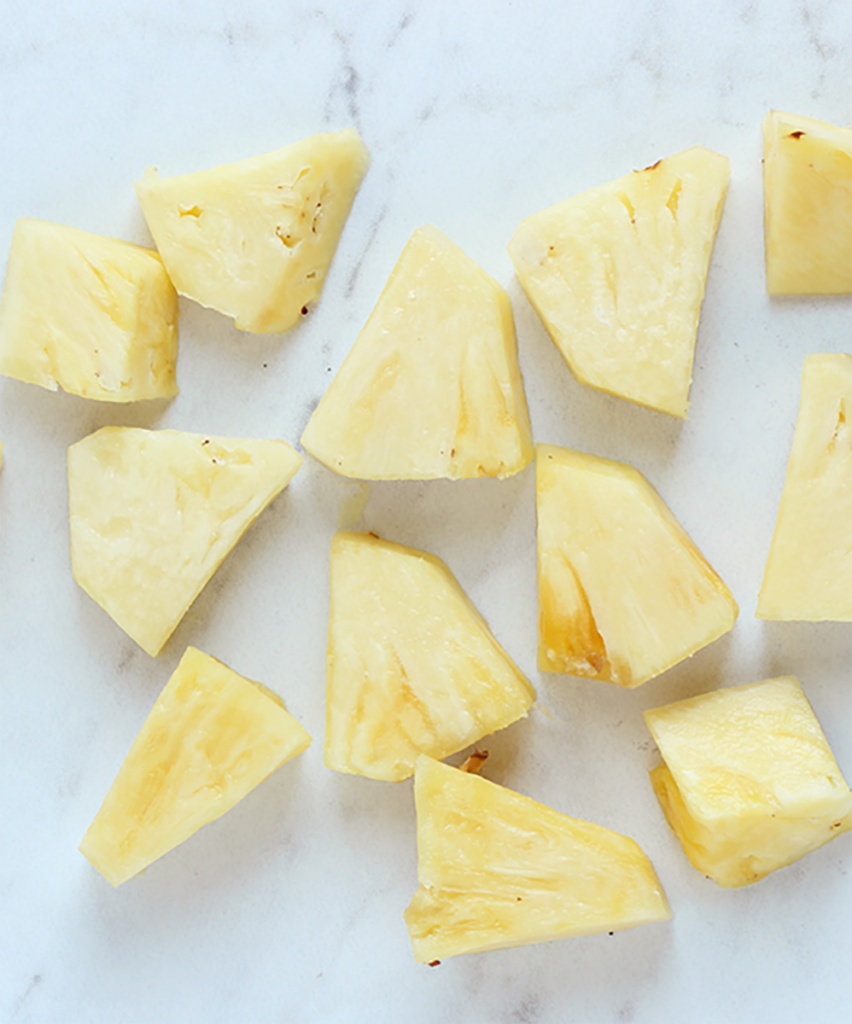 A photo of how to cut pineapple with chunks of pineapple on a counter