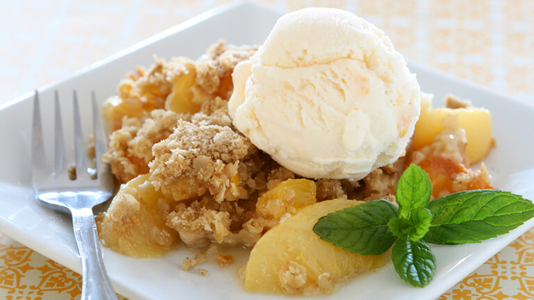 Peach crisp on a plate with ice cream.