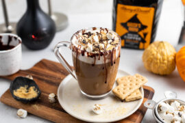 Coffee cocktail with roasted marshmallows in a mug surrounded by ingredients.