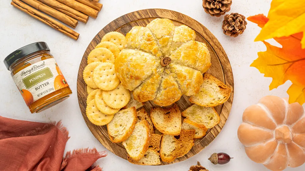 Pumpkin baked brie on a platter with crackers and sliced baguette.