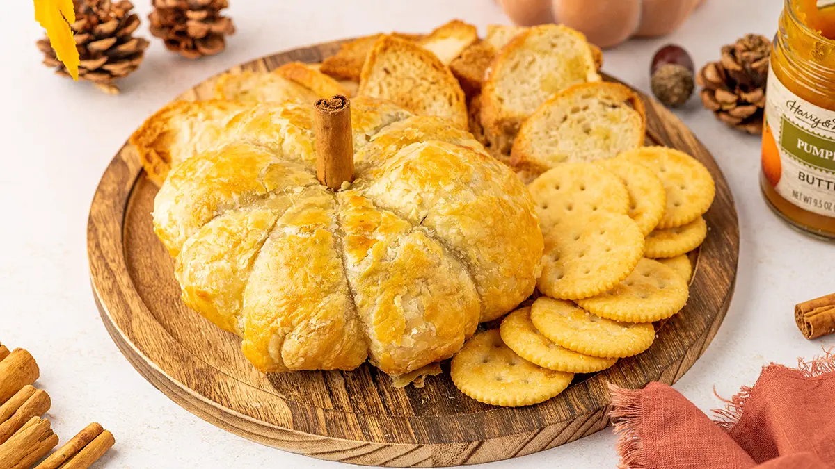 Pumpkin baked brie on a platter with crackers.