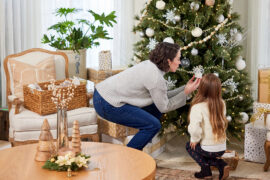 Woman and young girl putting up Christmas decorations.