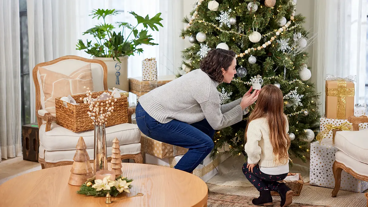 Woman and young girl putting up Christmas decorations.