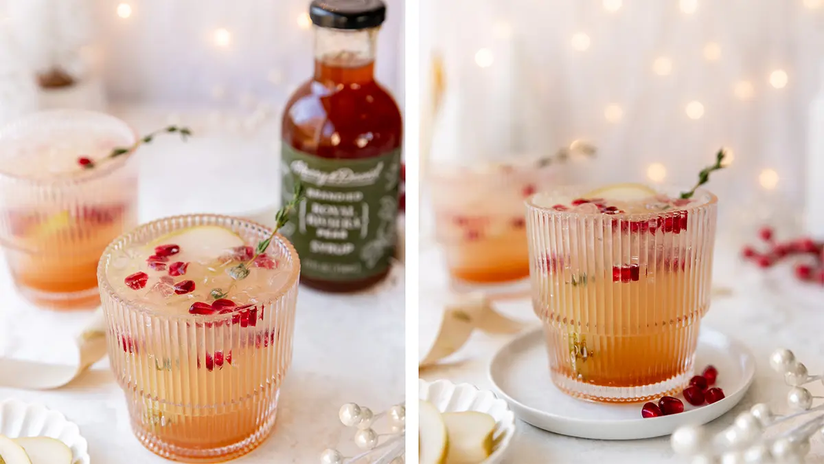 Pear kombucha mocktail in a glass with a slice of pear, pomegranate seeds, and thyme.