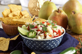 Pear salsa in a bowl surrounded by whole pears and tortilla chips