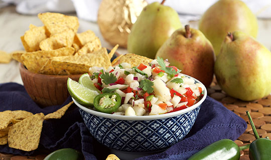 Pear salsa in a bowl surrounded by whole pears and tortilla chips