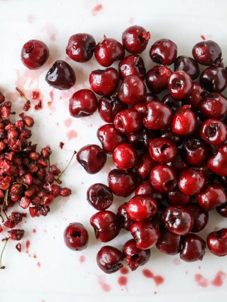 A photo of cherry crisp with pitted cherries on a cutting board.