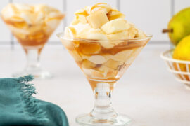 Pear trifle recipe in two glasses with a couple of pears in the background.