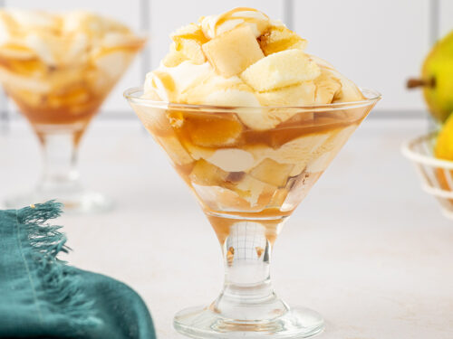 Pear trifle recipe in two glasses with a couple of pears in the background.