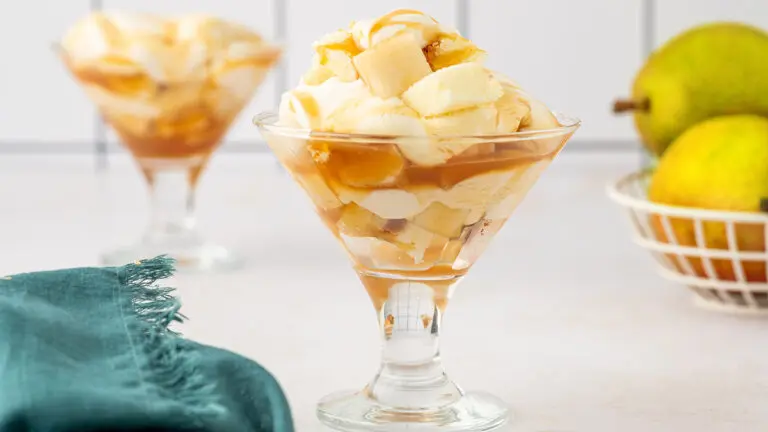 Pear trifle recipe in two glasses with a couple of pears in the background.