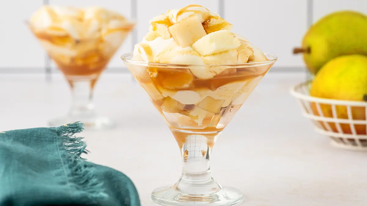 Pear trifle recipe in two glasses with a couple of pears in the background.