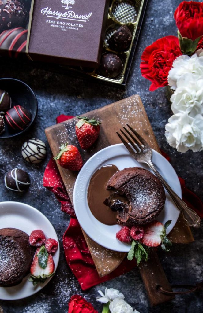 Valentine's Day dessert ideas with a two chocolate lava cakes on plates surrounded by strawberries and truffles.