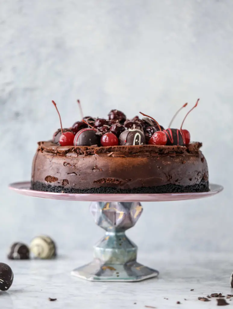 Valentine's Day dessert ideas with a chocolate cherry cheesecake topped with truffles on a platter.