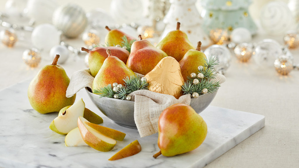 A photo of christmas pears on a table with glassware in the background.