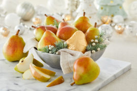 A photo of christmas pears on a table with glassware in the background.