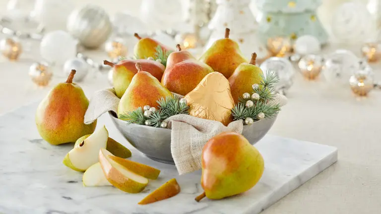 A photo of christmas pears on a table with glassware in the background.