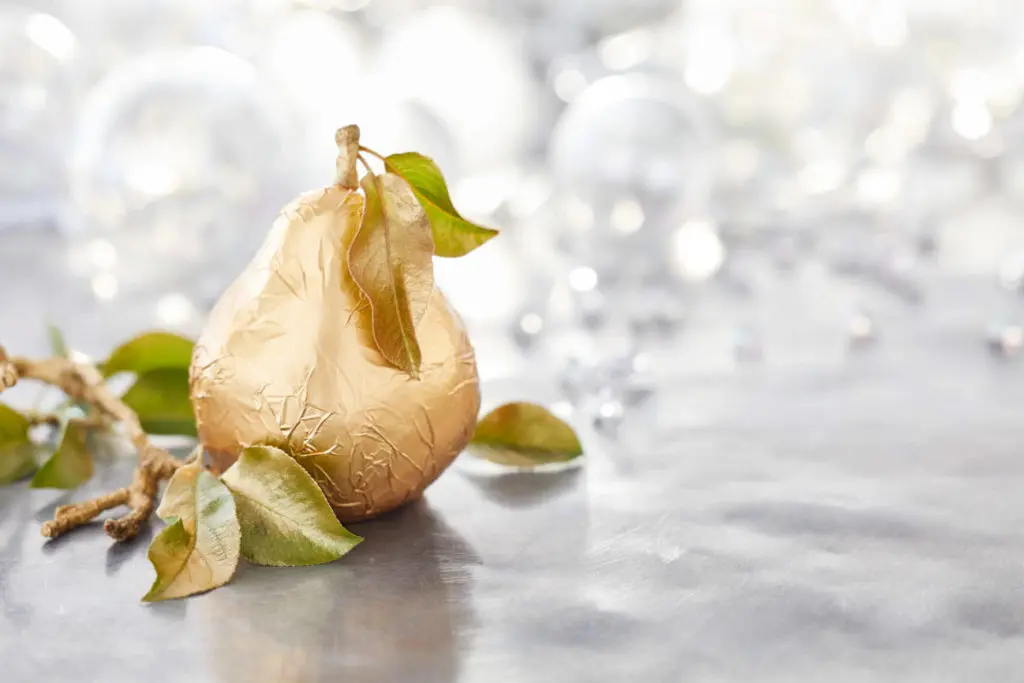A photo of christmas pears with a golden wrapped pear and silver lights in the background.