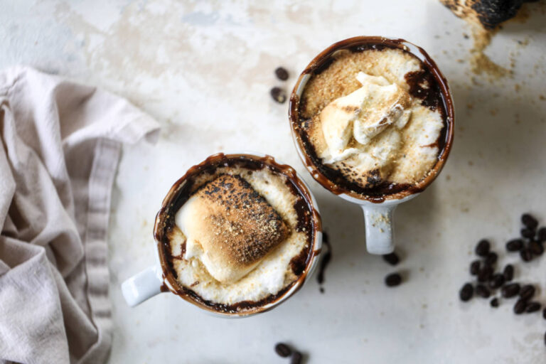 A photo of a mocha recipe with two mugs of coffee with toasted marshmallows on top