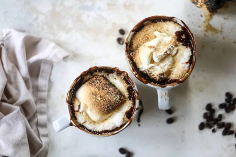 A photo of a mocha recipe with two mugs of coffee with toasted marshmallows on top