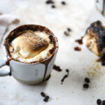 A photo of a mocha recipe with a mug of coffee with a toasted marshmallow on top.