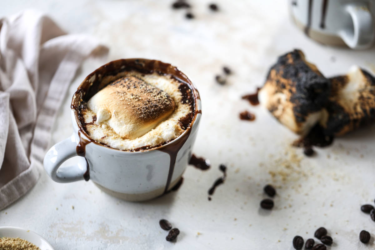 A photo of a mocha recipe with a mug of coffee with a toasted marshmallow on top.