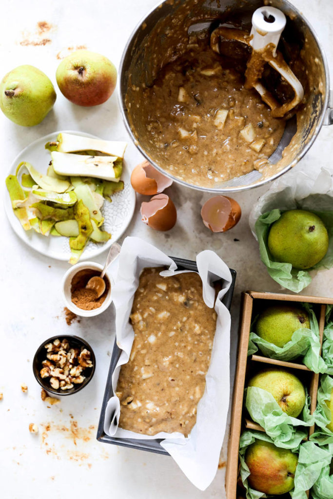 Chai spiced pear bread batter in a bowl with ingredients surrounding it.