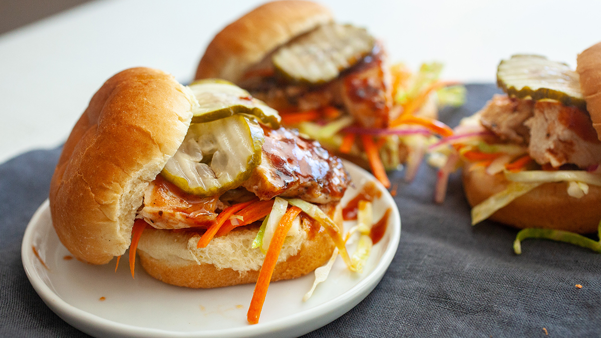 A photo of chicken sliders with a bottle of barbecue sauce next to them