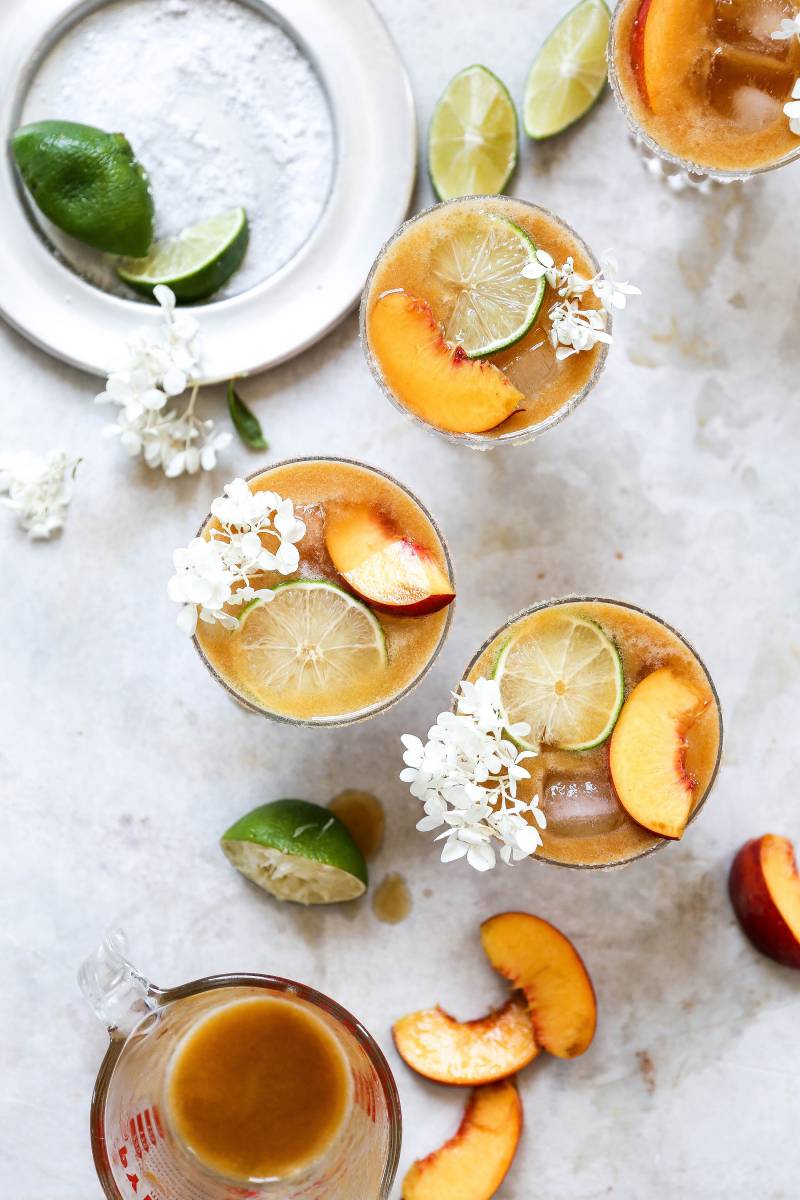 Peach margaritas surrounded by ingredients.