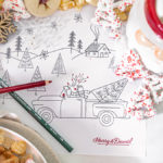 A photo of Christmas coloring pages surrounded by a mug of hot coco and cookies