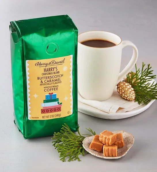 A photo of stocking stuffer ideas with a bag of Harry & David coffee next to a full mug of coffee surrounded by gold pinecones and evergreen boughs.