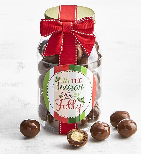 A photo of stocking stuffer ideas with a jar of malted milk balls decorated for the holidays.