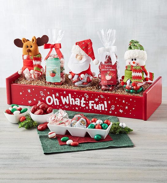 A photo of stocking stuffer ideas with a box of five individually wrapped holiday gifts with bowls of candy in front.