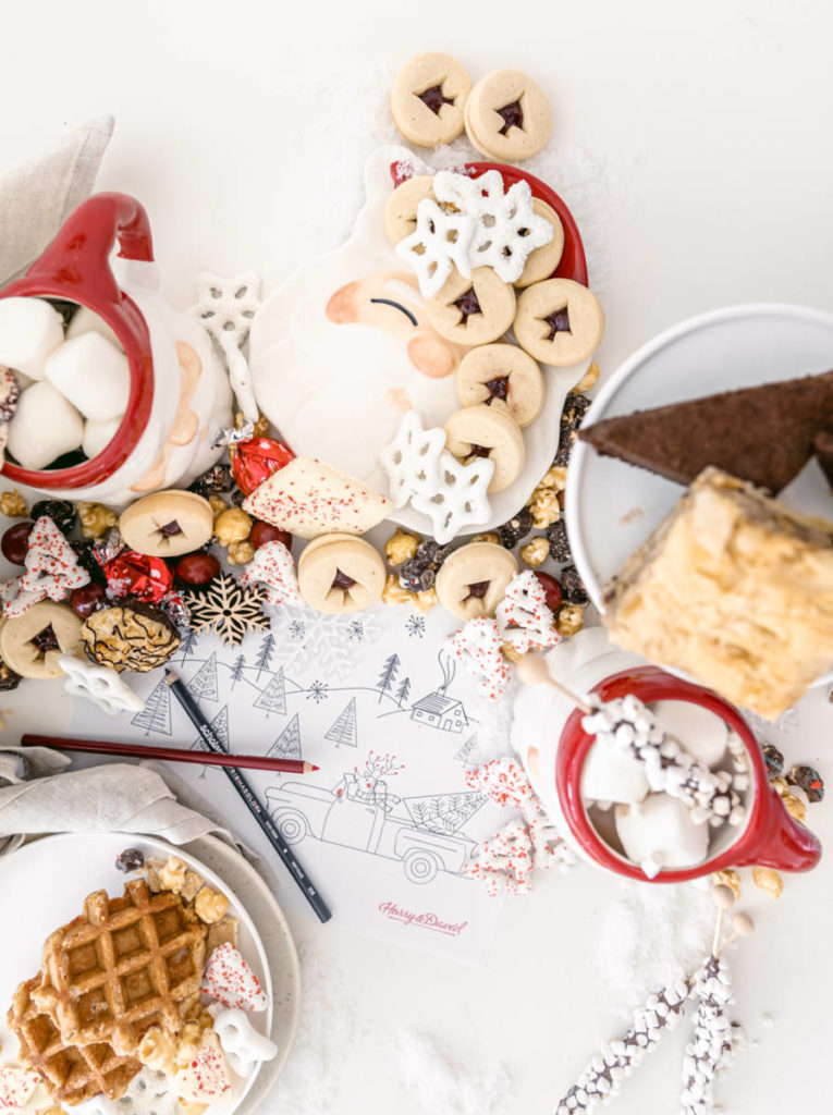 A photo of Christmas crafts for kids with a spread of cookies and waffles with a santa plate and mug