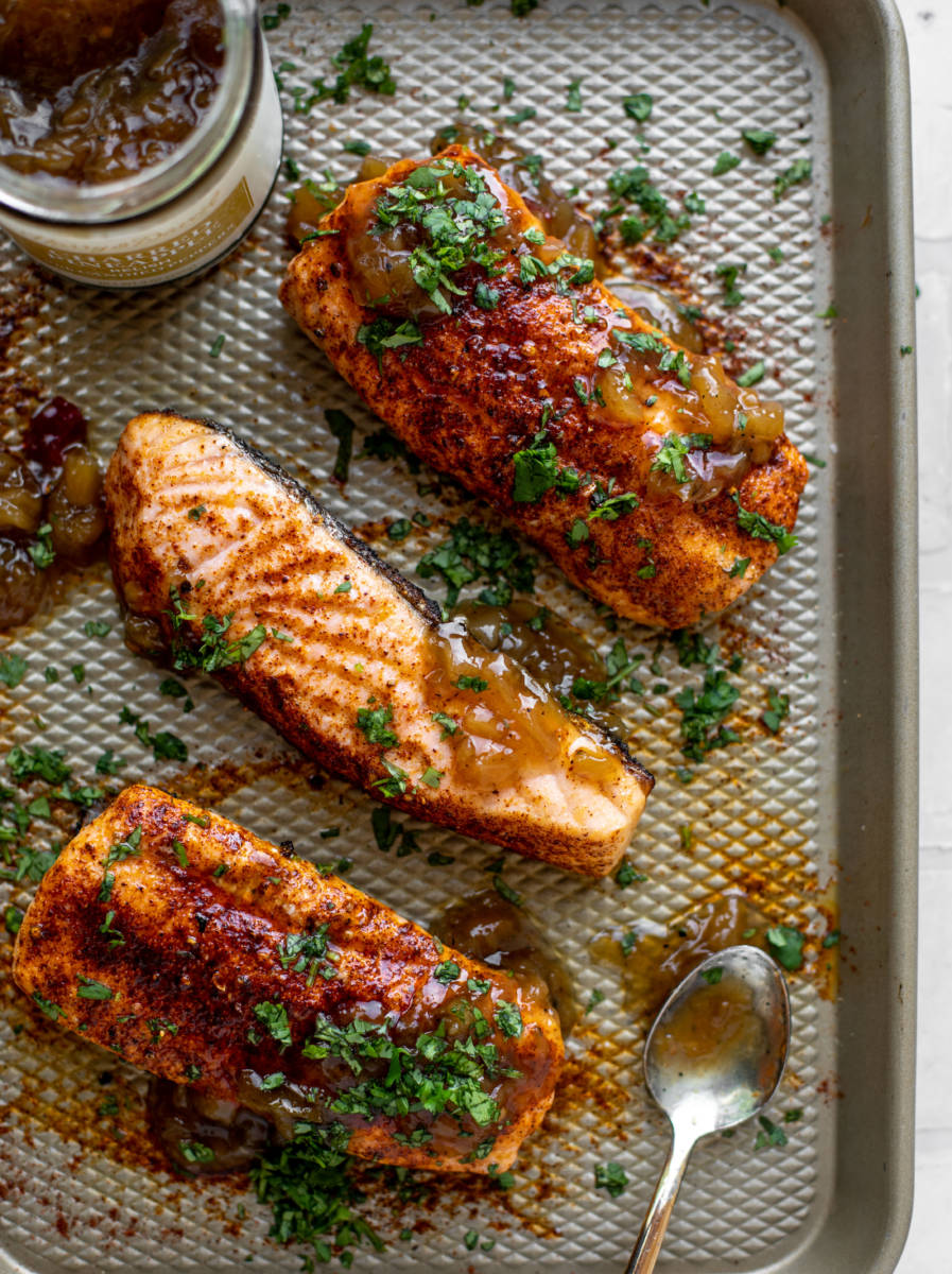 Grilled salmon recipe on a platter covered in pineapple relish.