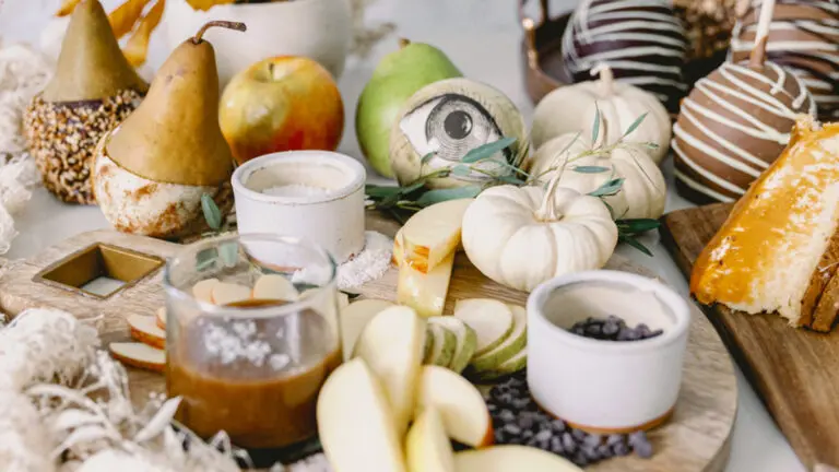 halloween snack board image - halloween themed snack board with caramel cheesecake, apples, and chocolate