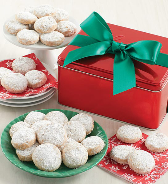 A photo of Christmas gifts under $30 with a red box with a green bow on it surrounded by plates of cookies