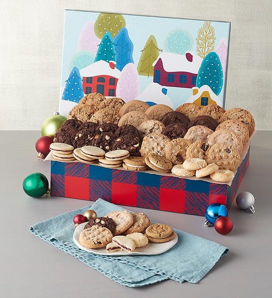 A photo of a gift guide with a box full of different kinds of cookies with a plate of cookies in front of the box.