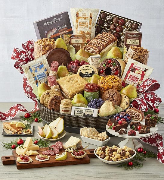 A photo of a gift guide with a basket full of baked goods, chocolate, fruit, and cheese.