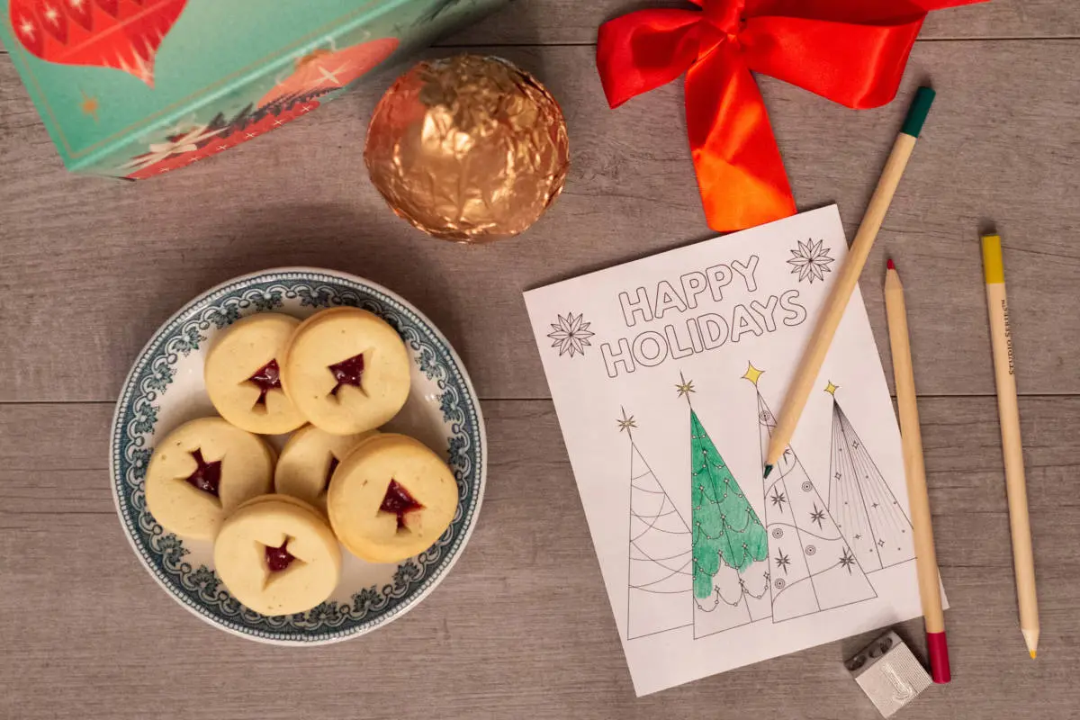 A photo of holiday spirit with a plate of Christmas cookies next to a half colored in picture of Christmas trees with pears sitting next to the picture.