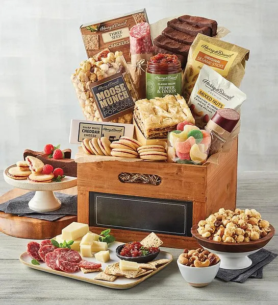 Best gift basket full of sweet and savory snacks surrounded by the same items on plates and platters.