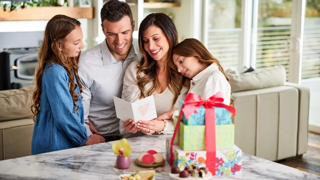 Best gift baskets with a family reading a card attached to a stack of presents.