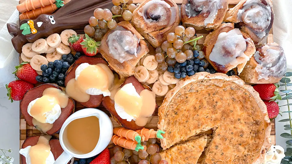 A photo of Easter brunch with a board full of quiche, eggs Benedict, and other brunch food.
