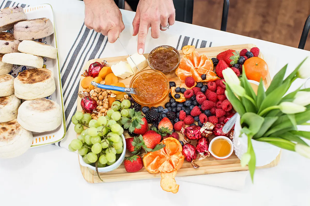 A photo of Easter meal with a spread of fruit and jams on a board.