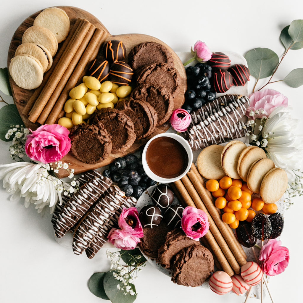 dessert board with cookies, fruit, and flowers