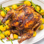A photo of chicken recipes with a roast chicken on a bed of roast vegetables